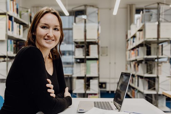 Studentin sitzt mit Laptop in der Bibliothek der Deutschen Sporthochschule