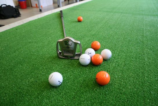 Golfbälle und Schläger auf grünem Grund
