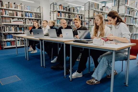 Studierende sitzen mit Laptops in der Bibliothek der Deutschen Sporthochschule
