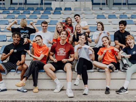 Studierende sitzen auf der Tribüne im Leichtathletikzentrum
