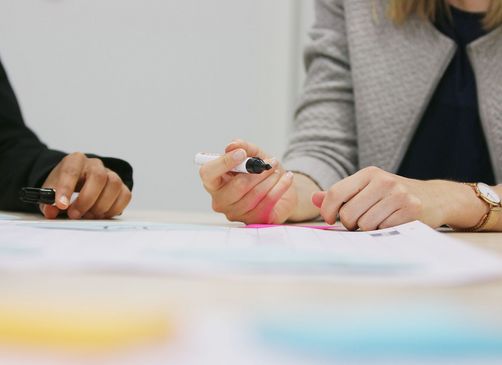 Zwei Personen beschriften einen Kalender, der auf dem Tisch liegt
