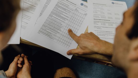 Studierende betrachten Fragebogen der Deutschen Sporthochschule
