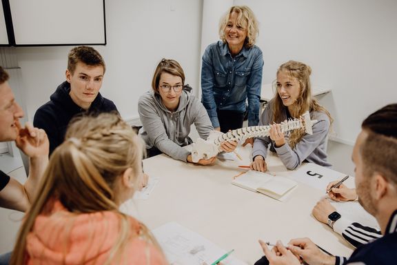 Studierende betrachten Modell einer Wirbelsäule in Gruppenarbeit
