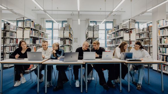 Studierende sitzen mit Laptops in der Bibliothek der Deutschen Sporthochschule
