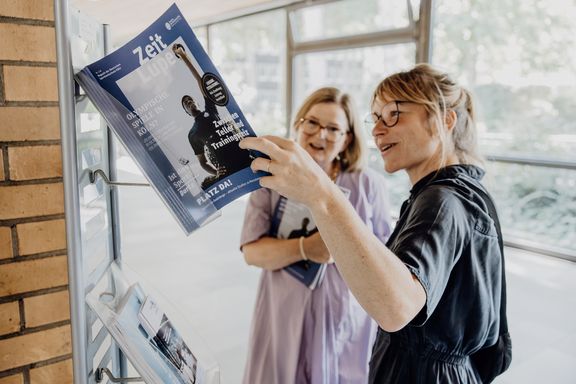 Zwei Mitarbeiterinnen der Spoho schauen sich im Foyer die neueste Ausgabe des ZeitLupen-Magazins an.
