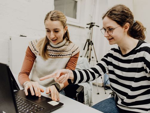 Zwei Personen betrachten Inhalte auf einem Laptop
