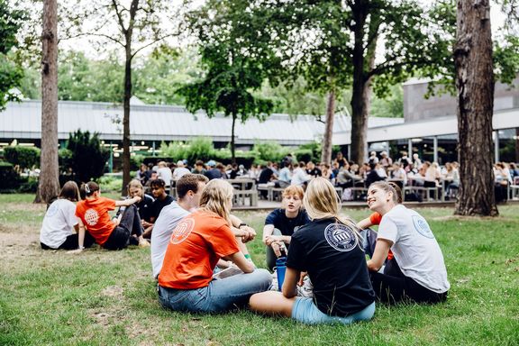 Studierende sitzen auf einer Wiese
