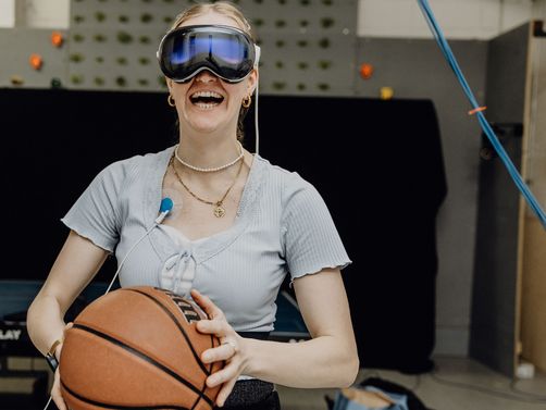 Probandin mit VR-Brille hält Basketball vor sich fest
