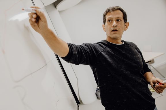 Dozent beschriftet Skizze am Whiteboard im Seminarraum
