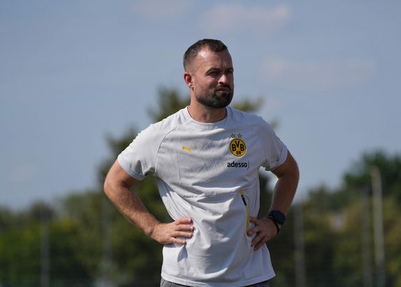 Das Foto zeigt Felix Hirschnagel, einen Mann mit einem weißen BVB-T-Shirt, welcher die Hände in die Seiten gestemmt hat.
