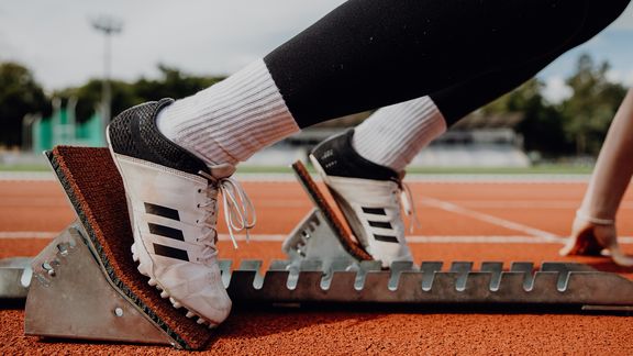 Nahaufnahme der Spike-Laufschuhe im Startblock auf der Laufbahn
