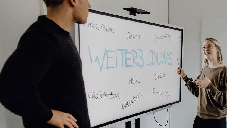 Fotos von zwei Personen vor Whiteboard mit dem Schriftzug "Weiterbildung"

