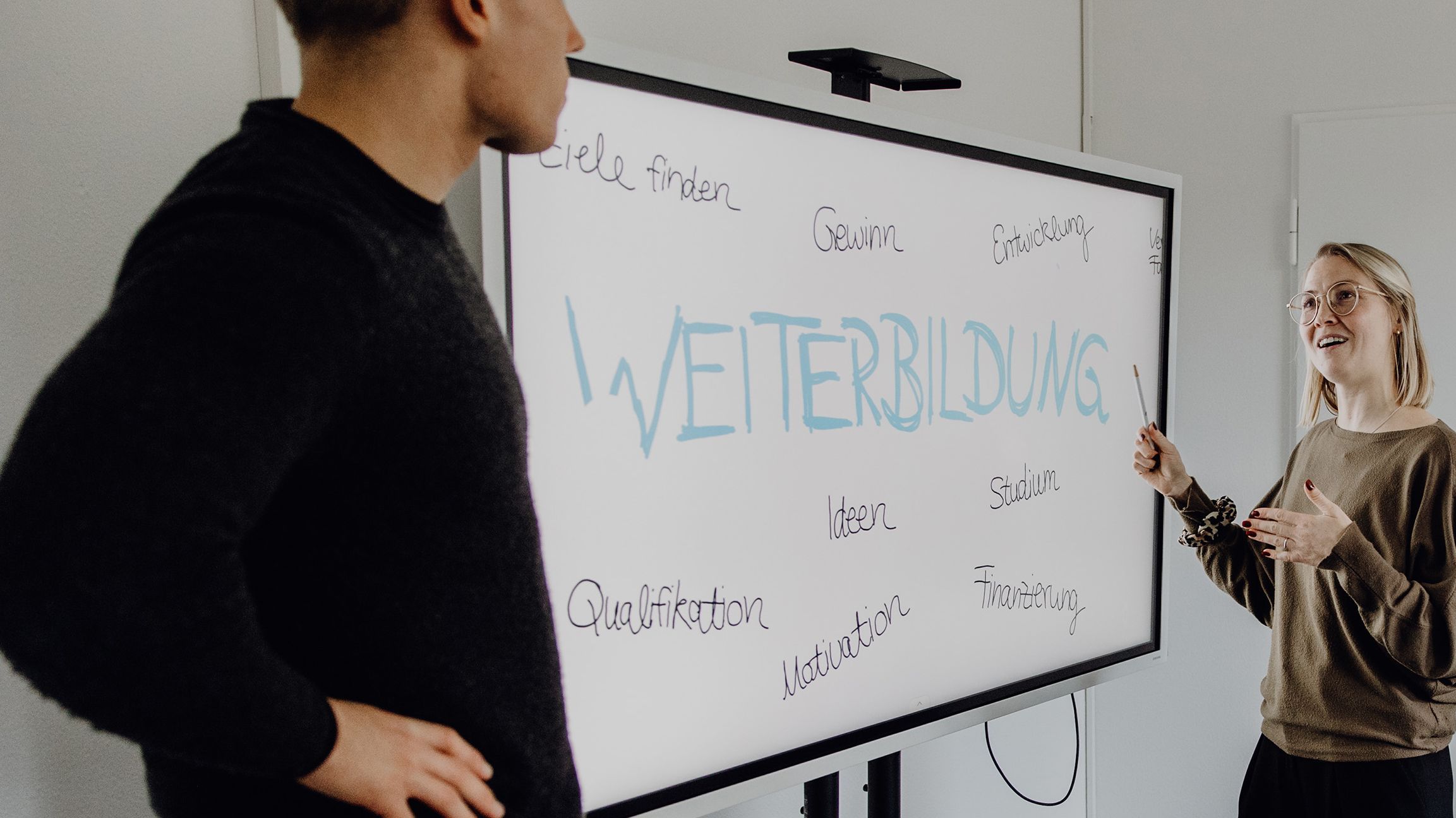 Fotos von zwei Personen vor Whiteboard mit dem Schriftzug "Weiterbildung"
