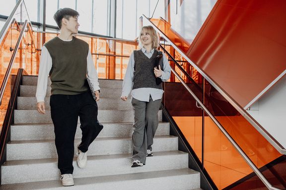 Zwei Studierende gehen die Treppen im Treppenhaus hinunter
