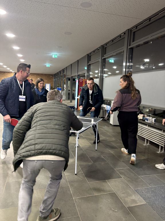 vier Personen spielen Tischtennis
