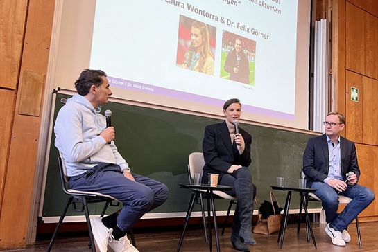 Laura Wontorra sitzt im Hörsaal und hält ein Mikro in der Hand