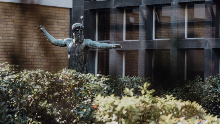 Außenbereich des Campus der Deutsche Sporthochschule mit steinerner Statue
