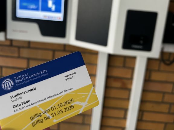 Ein Studierendenausweis wird vor das Validiergerät gehalten
