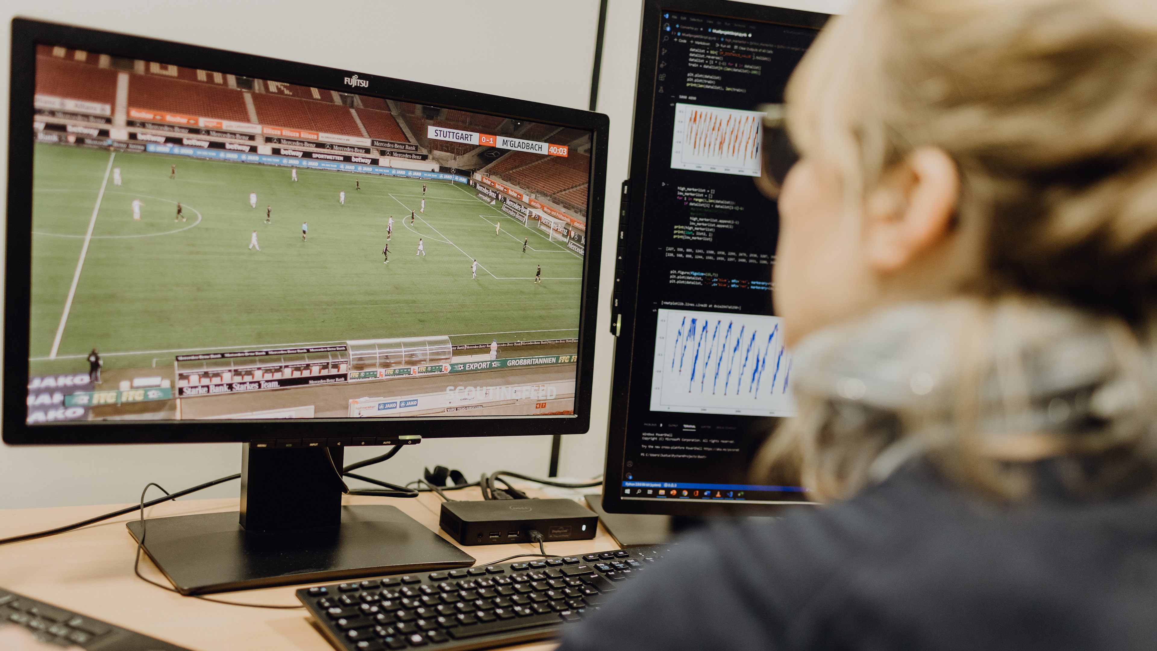 Foto von Person die auf linkem Bildschirm Fußballspiel und auf rechtem Bildschirm Programmiercode betrachtet
