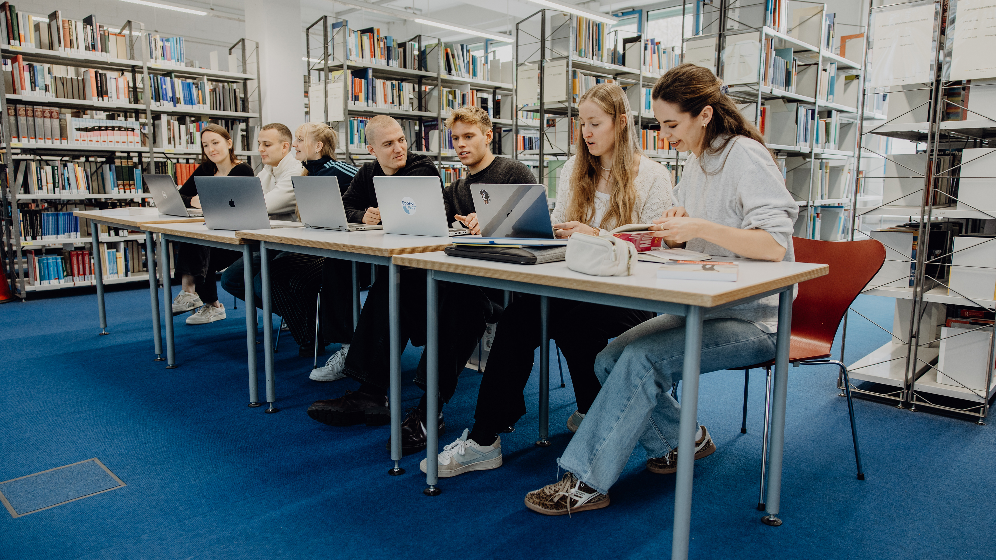 Studierende sitzen mit Laptops in der Bibliothek der Deutschen Sporthochschule
