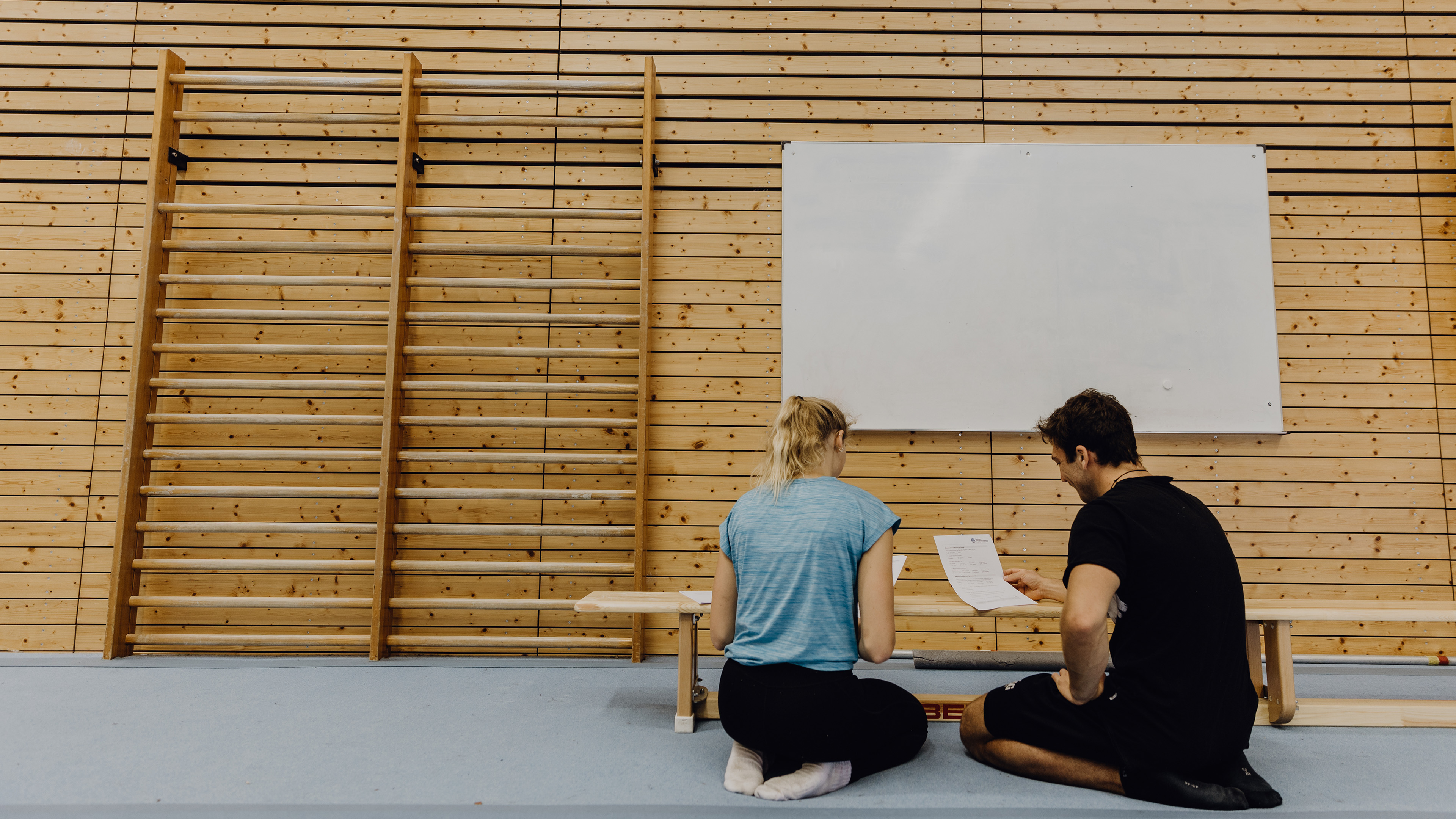 Studierende betrachten Formulare in der Turnhalle
