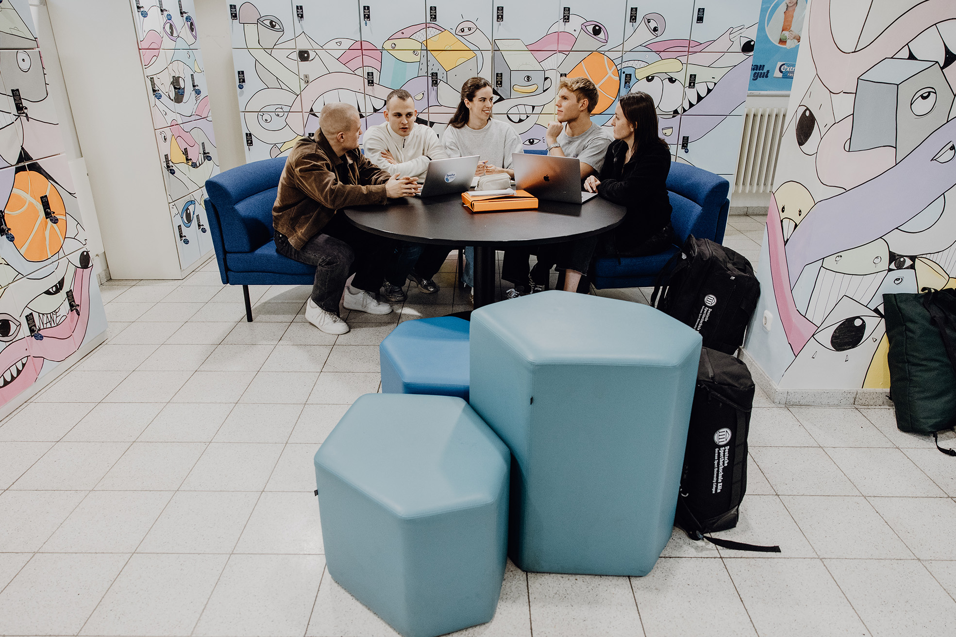 Studierende sitzen an einem runden Tisch im Foyer der Bibliothek

