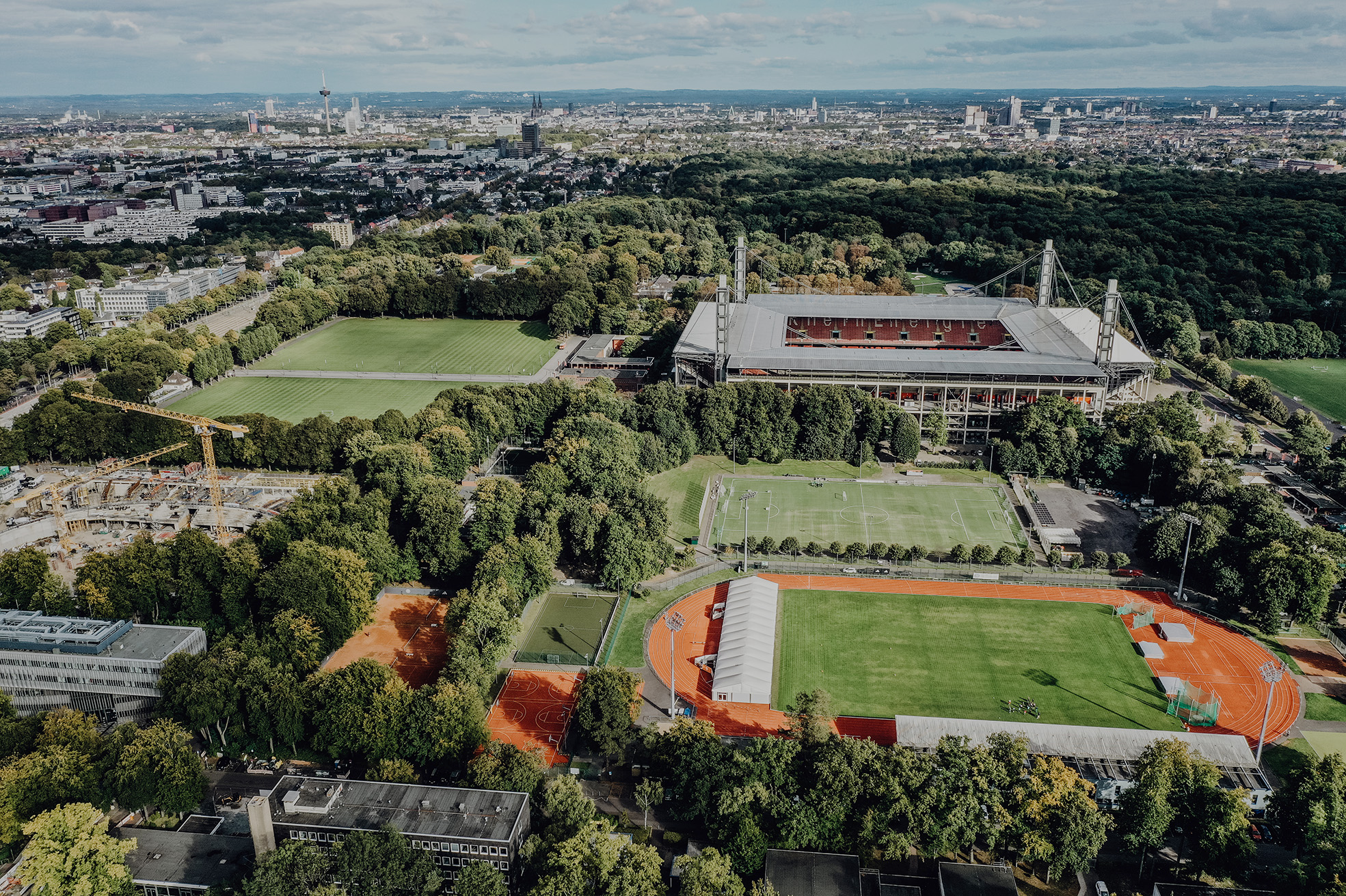 Luftaufnahme auf den Campus der Deutschen Sporthochschule mit Blick auf Köln im Hintergrund
